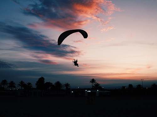 gliding silhouette of man parachuting under gray sky adventure